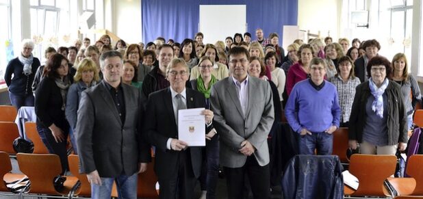 Bürgermeister Dr. Peter Paul Ahrens (M.) präsentiert gemeinsam mit allen Beteiligten die Kooperationsvereinbarung zum Übergang von der Kita zur Grundschule (Foto: Stadt Iserlohn).