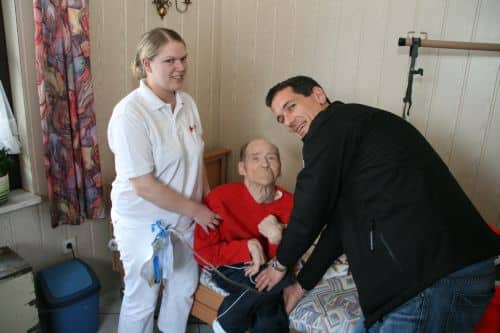 Foto: Vl. DRK-Schwester Christine Renard der Sozialstation Siegen erhält Hilfe von Jens Kamieth, um den Patienten Dieter Jäckel nach seiner Grund- und Behandlungspflege in seinen Spezialrollstuhl zu setzen