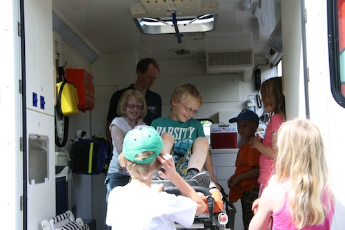 Die Kinder der Ferienspiele bekommen durch DRKler Christoph Enter (hinten) einen Krankenwagen erklärt und gezeigt. (Foto: DRK-Ortsverein Deuz)