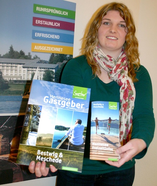 Janine Plugge, Auszubildende als Kauffrau für Tourismus und Freizeit im Team der TAG, präsentiert die beiden neuen Broschüren, die Hennesee FreizeitInfo und das Gastgeberverzeichnis (Foto: TAG „Rund um den Hennesee“).