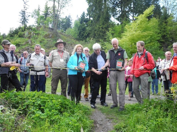 Landrat Paul Breuer und Bürgermeister Christoph Ewers durchschnitten, flankiert u.a. von Roswitha Still (TVSW) und Harald Knoche (Rothaarsteig-Verein), das Band (Foto: Gemeinde Burbach).