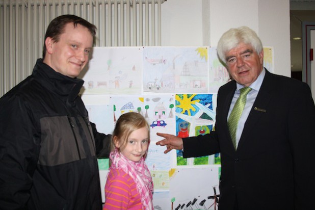 Gewinnerin Lina Althaus mit ihrem Vater und Landrat Paul Breuer vor dem Bild, das sie für die Klimakonferenz gemalt hat (Foto: Kreis Siegen-Wittgenstein).
