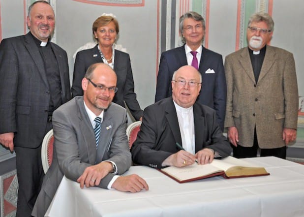 Bevor sich Erzbischof Hans-Josef Becker (vorne rechts) verabschiedete, trug er sich unter den Augen von Bürgermeister Christof Sommer (vorne rechts) sowie Dechant Thomas Wulf, Leiter des Dekanates Lippstadt-Rüthen, Annette Bergschneider, Wilhelm Börskens und Pfarrer Karl-Heinz Peter (stehend v.l.) ins Gästebuch der Stadt ein (Foto: Stadt Lippstadt).