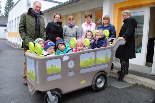 Im „Kita-Bus“ geht es hinaus nach Bigge und Olsberg: Elmar Reuter und Mareike Vollmer, Vorstandsvorsitzender und Geschäftsführerin der Bürgerstiftung „Wir in Olsberg“, überreichten den Krippenwagen an das Team des Familienzentrums Bigge (Foto: Stadt Olsberg).