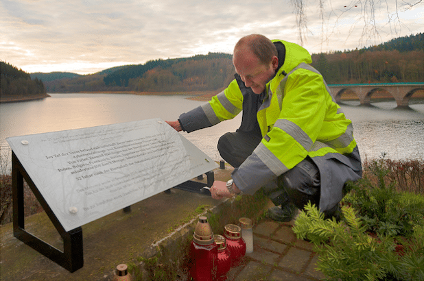 STL-Mitarbeiter Danny Müller befestigt die Tafel auf dem Sockel des gestohlenen Mahnmals (Foto: Stadt Lüdenscheid).