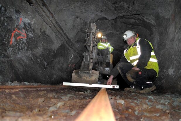 Arbeiten am Gleiskörper der Grubenbahn im Eickhoffstollen: Frank Hermes (vorne) und Dominik Pockholm „stopfen“ den Schotter unter den Schienen (Foto: Gemeinde Bestwig).