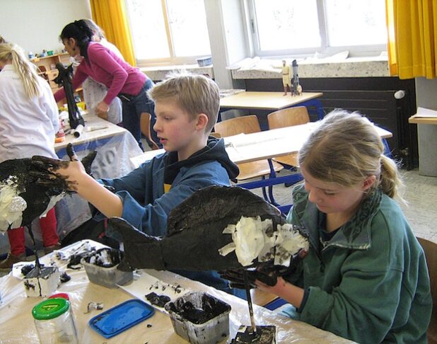 Max und Ida (Viertklässler der Luzia-Schule Oestereiden) zeigen keine Scheu, sich beim Modellieren ihrer Drahtfigur mit Kleber und Kleister die Hände schmutzig zu machen. Die Künstlerin Leni da Rocha Lordelo Gehlen hat sie zu Kreativität und Fantasie ermutigt (Foto: Christiane Reinke/Kreis Soest).