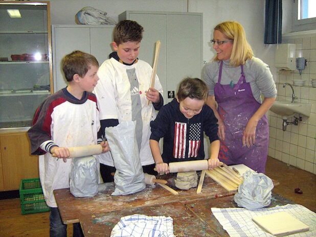 Benedikt, Joel und Jonas (Klasse 4b der Fürstenbergschule Hünningen, v. l.) stellen unter fachlicher Anleitung von Pascale Petit-Peters Keramikkacheln für die „Wand der Vielfalt“ her (Foto: Christiane Reinke/Kreis Soest).