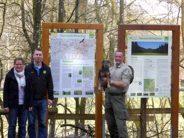 Von links: Kerstin Berens (Sauerland-Höhenflug), Karuna Eckel (Touristik-Gesellschaft Medebach mbH) und Ranger Andreas Vogt (Landesbetrieb Wald und Holz NRW) an der neuen Tafel auf dem Wanderparkplatz Orketal - Quelle: Sauerland-Tourismus e.V.