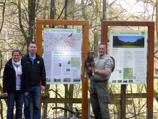 Von links: Kerstin Berens (Sauerland-Höhenflug), Karuna Eckel (Touristik-Gesellschaft Medebach mbH) und Ranger Andreas Vogt (Landesbetrieb Wald und Holz NRW) an der neuen Tafel auf dem Wanderparkplatz Orketal - Quelle: Sauerland-Tourismus e.V. 