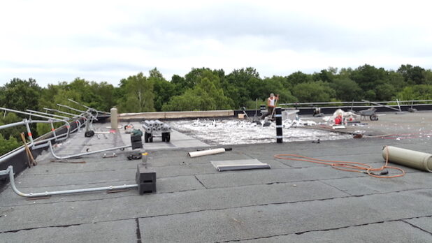 Ein Arbeitsplatz in luftigen Höhen. Bevor das Dach saniert und gedämmt werden kann, müssen die alten Baustoffe beseitigt werden (Foto: Gemeinde Neunkirchen).