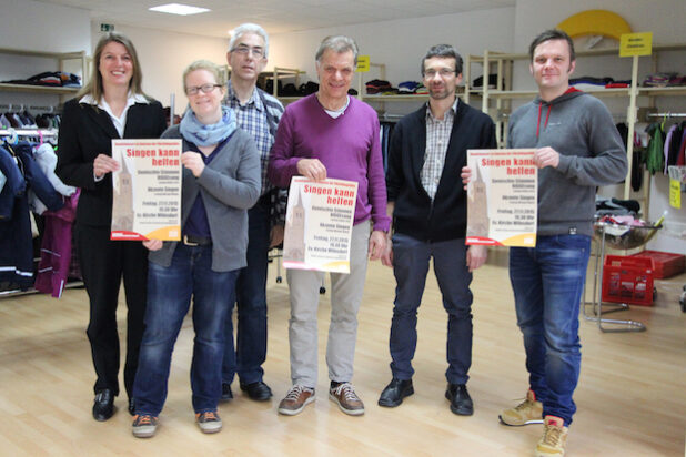 Im neueröffneten Laden des Ökumenischen Netzwerks Wilnsdorf warben die Veranstalter fürs Benefizkonzert. V.l.n.r.: Wilnsdorfs Bürgermeisterin und Schirmherrin Christa Schuppler, Sonja Sabel und Reiner Füchtenschnieder (beide Ökumenisches Netzwerk Wilnsdorf), „Akzente“-Dirigent Michael Blume, Pfarrer Christoph Otminghaus sowie Volker Arns, Chorleiter der „Gemischten Stimmen BIGGEsang“ (Foto: Gemeinde Wilnsdorf).