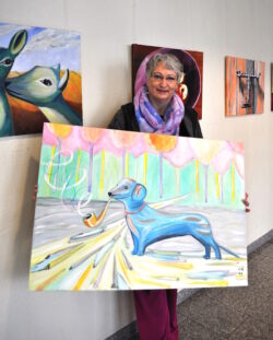 Anna Mira Lindholm hält ihren „Sherlock“ in den Händen und stellt weitere farbenfrohe Werke im Marienkrankenhaus aus (Foto: Marienkrankenhaus Soest).