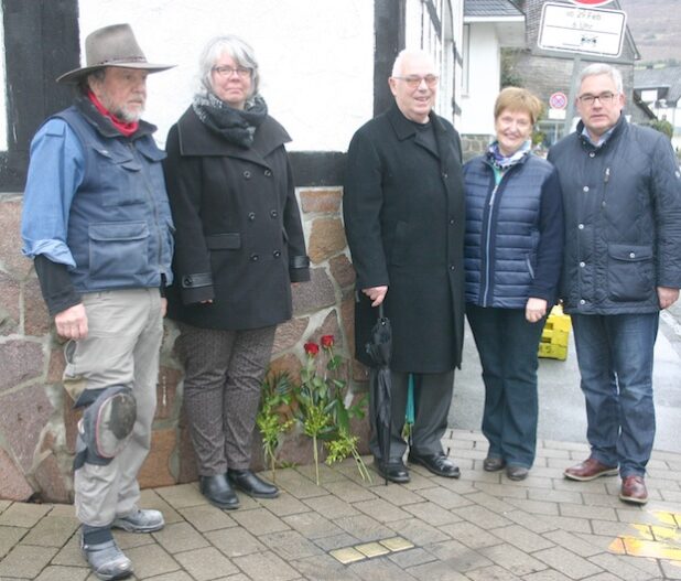 Der Kölner Bildhauer Gunter Demnig (li.) verlegt die Stolpersteine persönlich vor dem Haus Sachsenecke 6, in dem Familie Schild lebte, bevor sie nach London und Südafrika flüchtete. Mit im Bild: Bürgermeister Wolfgang Fischer (re.) und Vertreter des Heimatbundes Heimatbund-Vorsitzende Ursula Balkenhol. Foto: Stadt Olsberg 