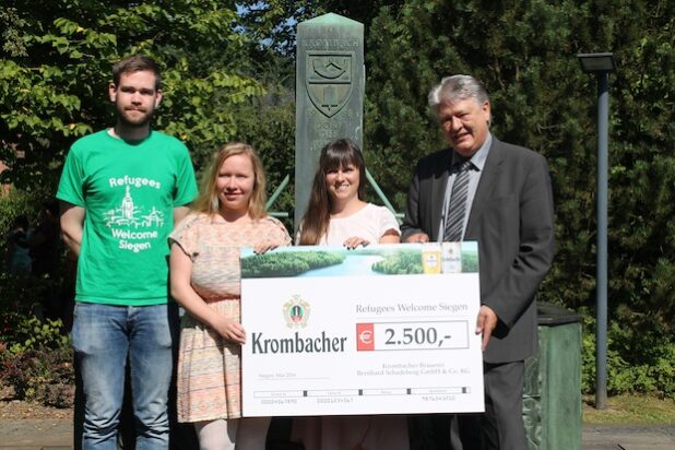 Stellvertretend für alle ehrenamtlichen Helfer nahmen Tobias Holzhauer, Ina van der Biesen und Jennifer Heinz den symbolischen Spendenscheck von Axel Brinkmann entgehen (v.l.n.r.). Quelle: Krombacher Brauerei Bernhard Schadeberg GmbH & Co. KG