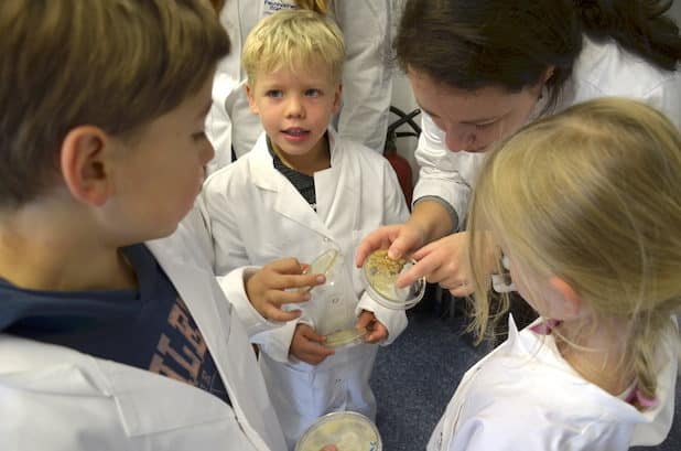 1.Gemeinsam mit FH-Mitarbeiterin Renata Szweda betrachten die Kinder ihre Petrischalen mit Bakterien - Quelle: Fachhochschule Südwestfalen
