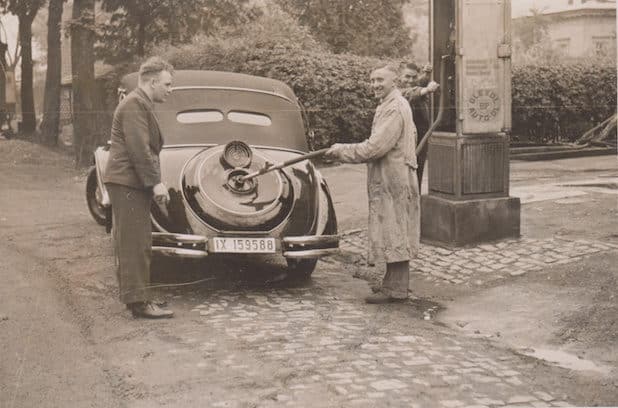 An der Tankstelle der Autowerkstätte und Fahrschule der Gebrüder Becker, Ende der 1920er Jahre – Im Kittel ist Karl Becker abgebildet. Rechts oben kann man die Villa Rentzing (heute: Realschule/Sekundarschule) erkennen - Quelle: Marsberger Geschichten - Schlüssel zur Vergangenheit e. V.